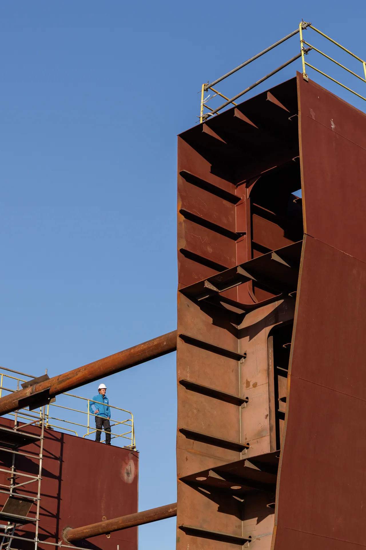 Bloc de coque en acier dressé sur le chantier naval, un ouvrier sur l’échafaudage