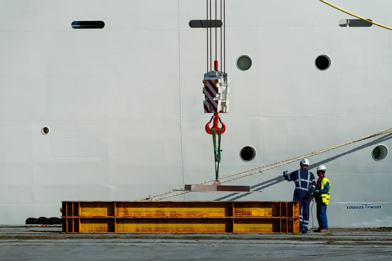 Crochet de grue soulevant une charge sur le quai, le long de la coque