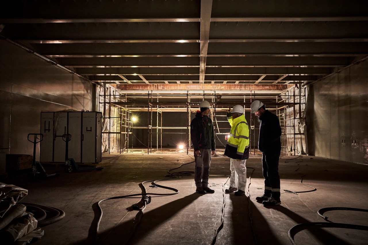 Trois membres de l’équipe en discussion dans la cale d’un navire en chantier