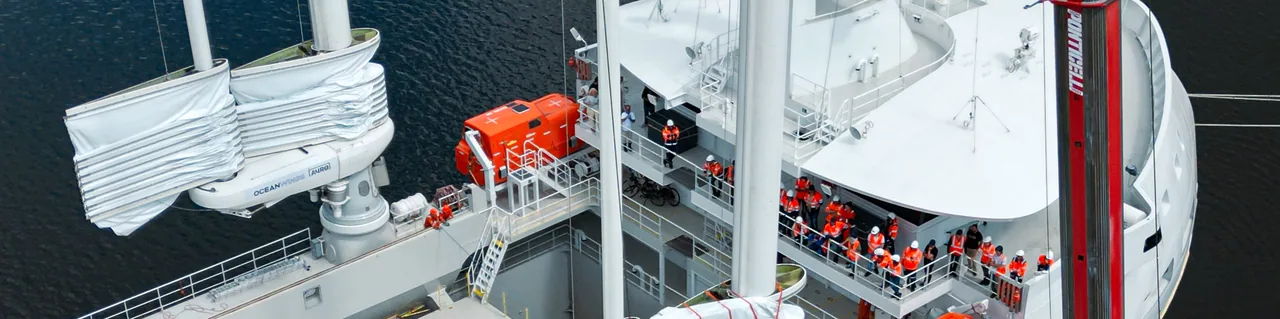 Équipage en combinaisons orange sur le pont du Canopée à quai, pendant la pose des ailes à la grue
