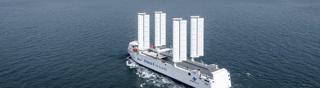 Le Canopée naviguant au large sous ses quatre ailes rigides, sillage blanc sur une mer sombre