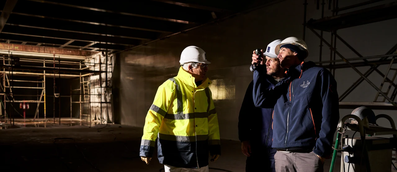 Trois membres de l'équipe en casques dans la cale d'un navire en chantier